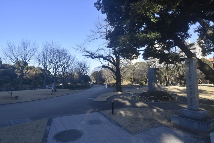 もとは水戸徳川家の下屋敷であったことを示す碑が建つ。奥に築山や池も見える。