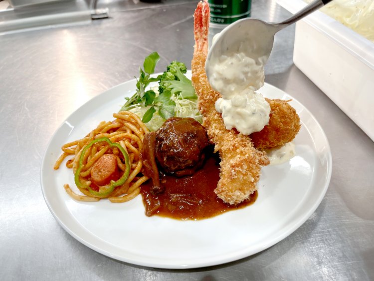 実際、厨房では人間のシェフが特製のタルタルソースを揚げたてのエビフライとカニクリームコロッケにのせていた。