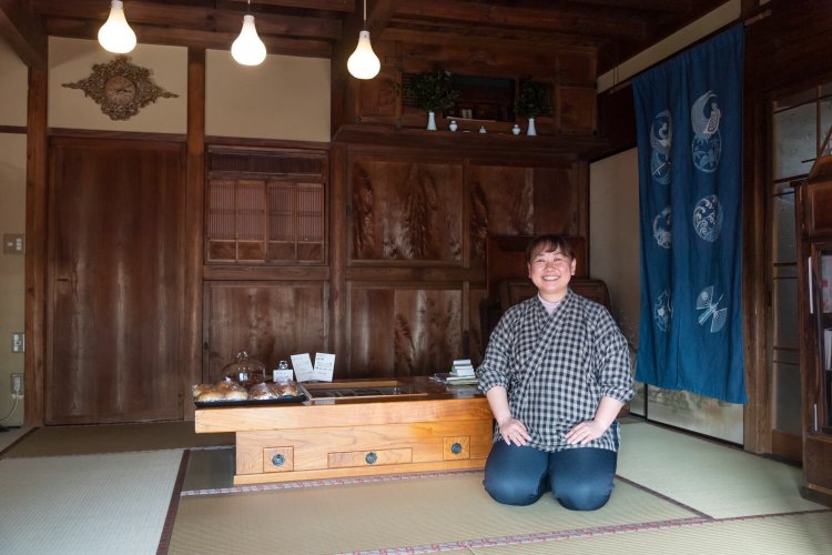 客を玄関でお見送りする女将さんは作務衣姿がトレードマーク。元大工の義父作の長火鉢でパンも販売。