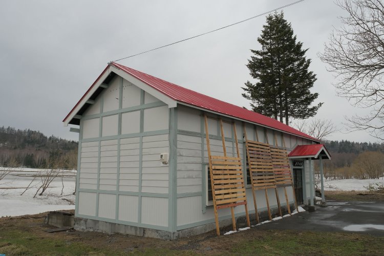 見事に蘇った添牛内駅舎。くたびれていた外壁も張り直した。窓は冬季なので雪囲いされている。屋根は見違えるように朱色に輝き、損傷していた箇所もきれいに直っていた（2023年4月）。