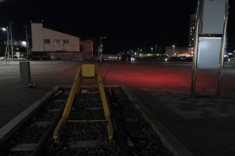 夜、車止めから北側を見ると黒い線が続いている。北ふ頭へ続いていた貨物線の跡をタイルで表現している（2023年4月18日）。