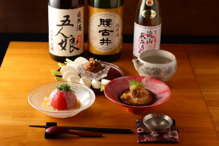 “房州炊き”より、しいたけ390円（右）、トマトクリームチーズ680円（左）。地元野菜を使ったおばんざいも豊富。地酒や流山本みりんカクテルとともに。