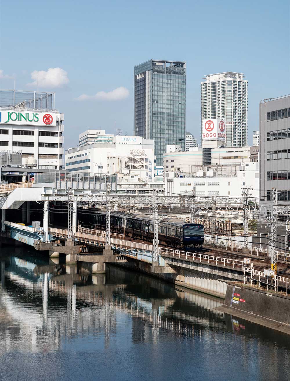 帷子川に架かる大きな平沼橋から横浜駅西口方面を望む。凛々しいブルーが噂の相鉄線。