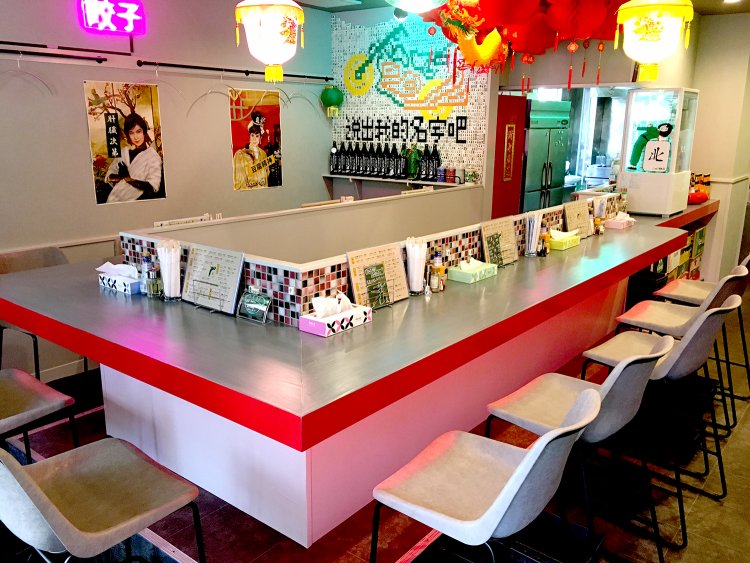 店内の正面にはコの字型のカウンター席。右奥には4人掛けのテーブル席が2つある。