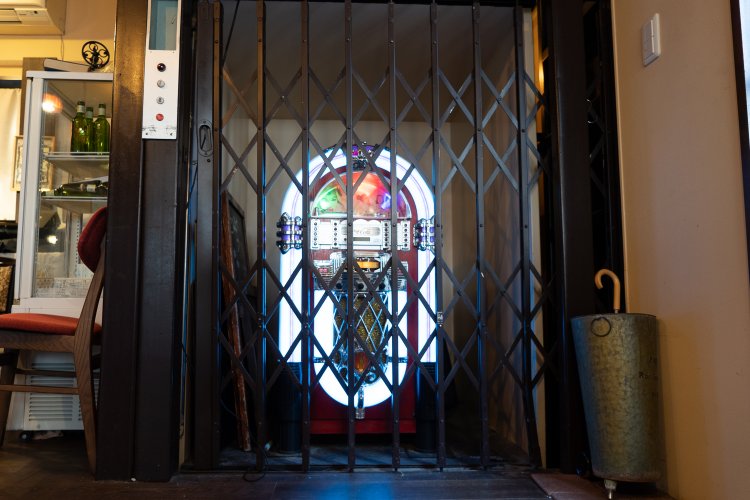 今は使われていない業務用エレベーター。中に置かれたジュークボックス型のスピーカーからはオールディーズの音楽が流れている。