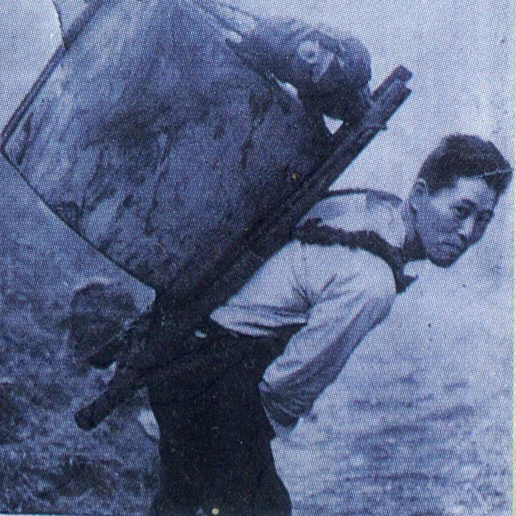 1958年の福島伊勢松さん。背負っている臼は重さ50kg。