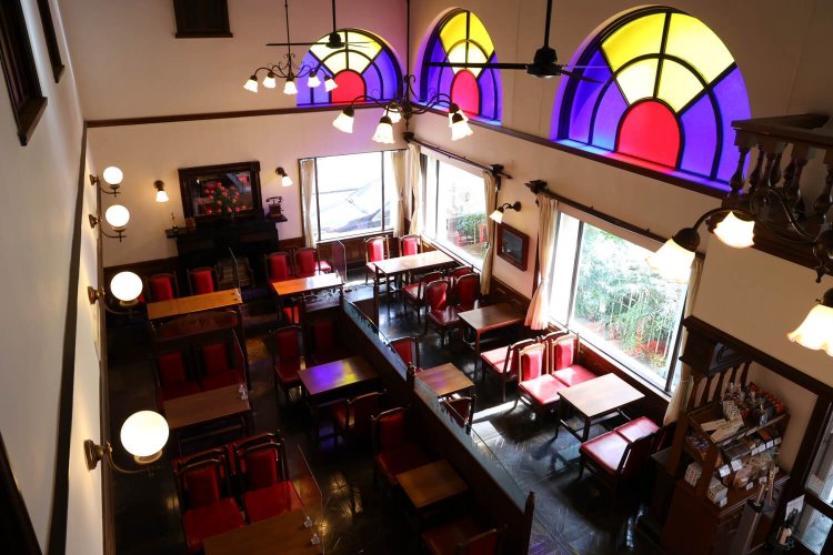 日の光が差す時間はモダンなステンドグラスが印象的。座面を張り替えながらも使い続ける木製椅子が愛らしい。