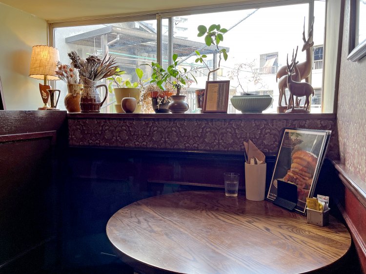 窓際の植物たちや、木製のオブジェ、古いランプがおしゃれ。