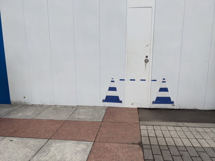 工事現場の囲いに貼られた二次元のカラーコーン。新宿にて。