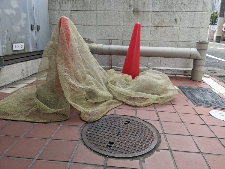 羽衣のようにゴミネットがかけられたカラーコーン。