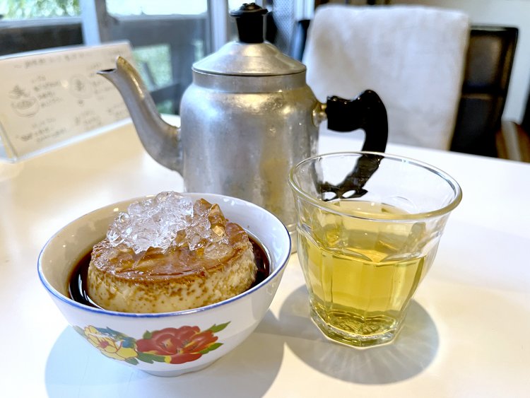 ほろ苦いコーヒーに浮かんだ甘く濃厚なプリン・バインフラン。クラッシュアイスが乗っているところが暑い国らしいデザートだ。単品のお茶セットは900円。