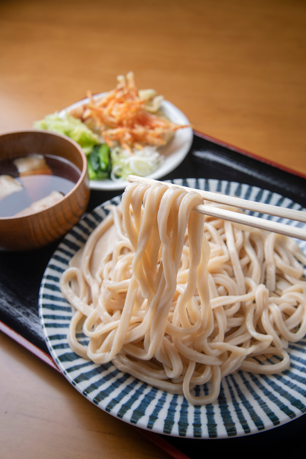 普通盛り 天ぷら付き 肉汁850円（休日価格）。天ぷらは旬の野菜のかき揚げなど3品ほど。肉汁変更は無料。平日は各うどん50円引きで提供。