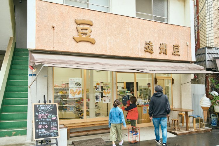 商店街で目を引く看板。店先のベンチやピーナッツ型テーブルで憩える。