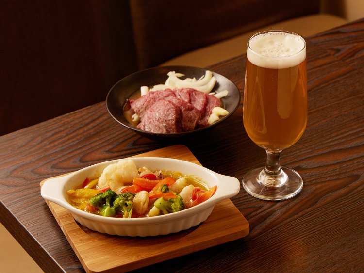 2022年に飲食スペースを新設。軽食だけのつもりがお客さんの要望でメニューが増加。馬刺し748円や海鮮アヒージョ660円も。グラス385円。