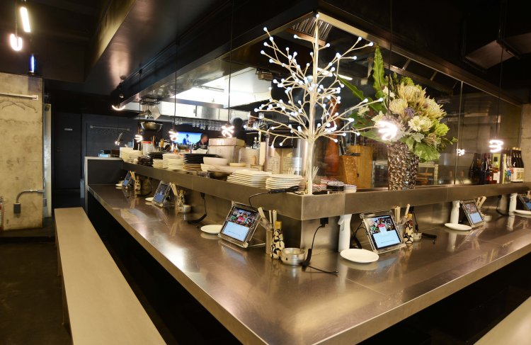 ステンレス板を張ったカウンター席。入り口正面ではエキゾチックな花が迎えてくれる。