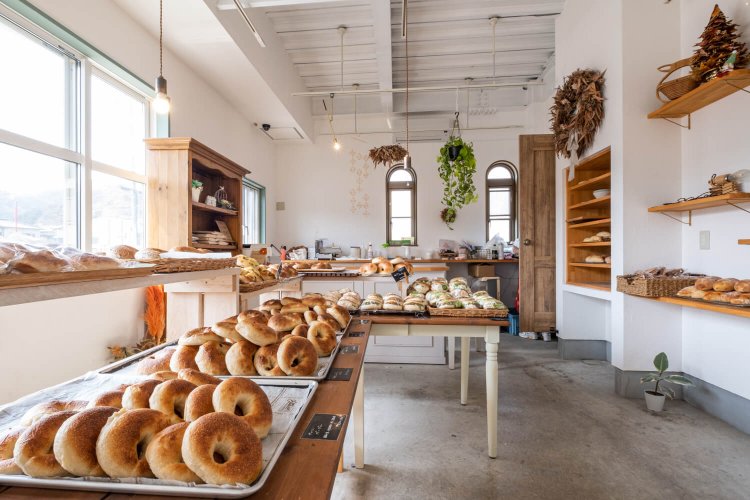 ベーグルがずらりと並ぶ白を基調とした店内は、柔らかい外光も印象深い。開店と同時に飛ぶように売れていく様子も圧巻だ。