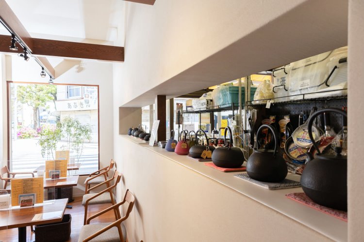 鉄瓶の向こうの金物店には日用品が積み上がる。