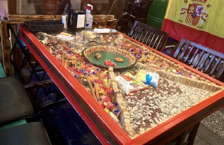 スペインで購入した雑貨やグミ、パスタ、ひまわりの種、パエリア鍋などが飾られるガラステーブル。