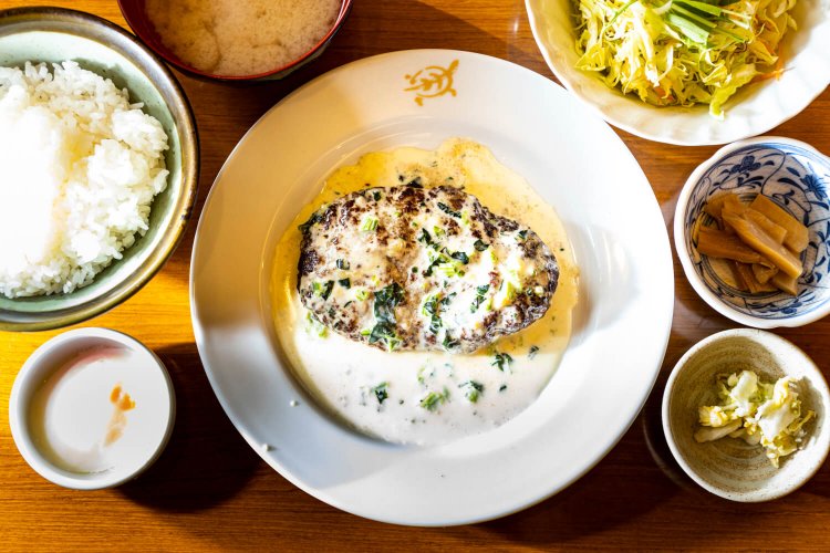 へそハンバーグ定食1100円。温泉卵100円（左下）と崩したハンバーグをごはんに混ぜて食べるのもおすすめ。