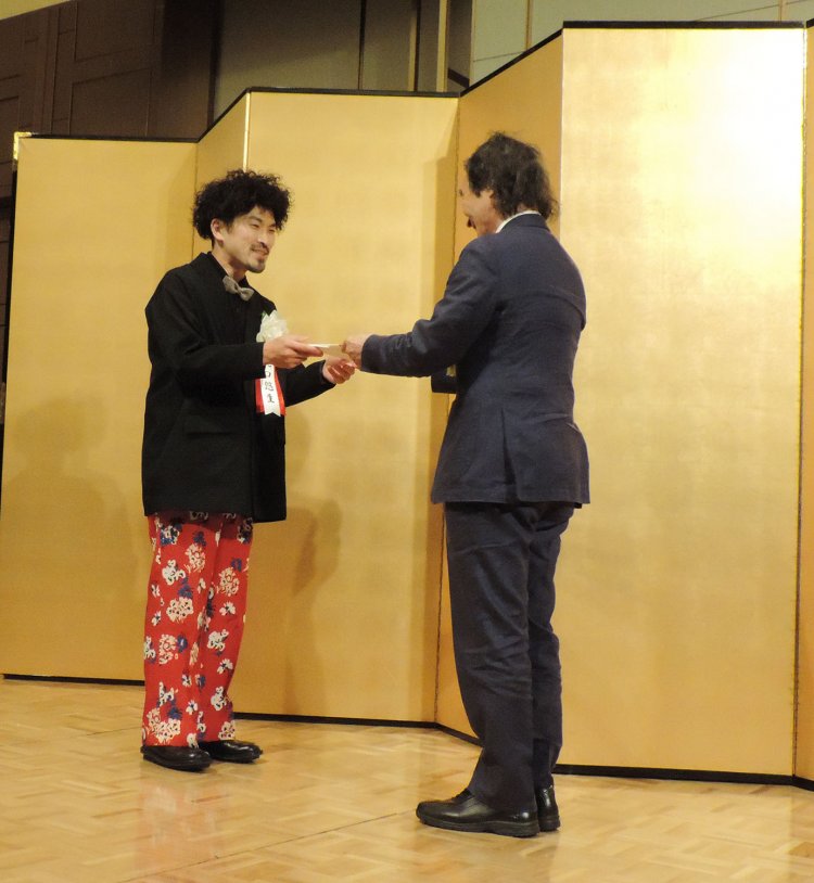 辻原氏から贈呈される滝口氏（左）。