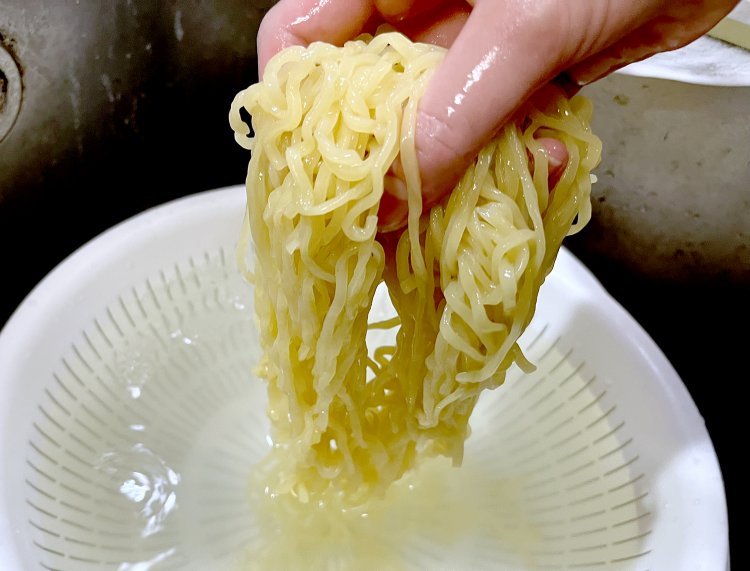 茹であがった中太麺を冷水でしめる。