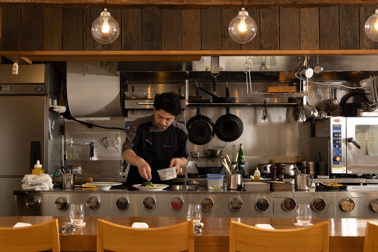 お客さんの目線の位置に調理台を設えたオープンキッチン。カウンター席を指定する人も多い。