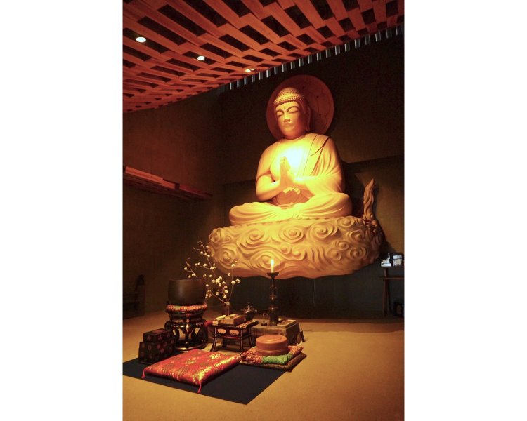 灯明（とうみょう）が呼吸のように静かに揺れる堂内。木の持つみずみずしさと温かさが満ちている。