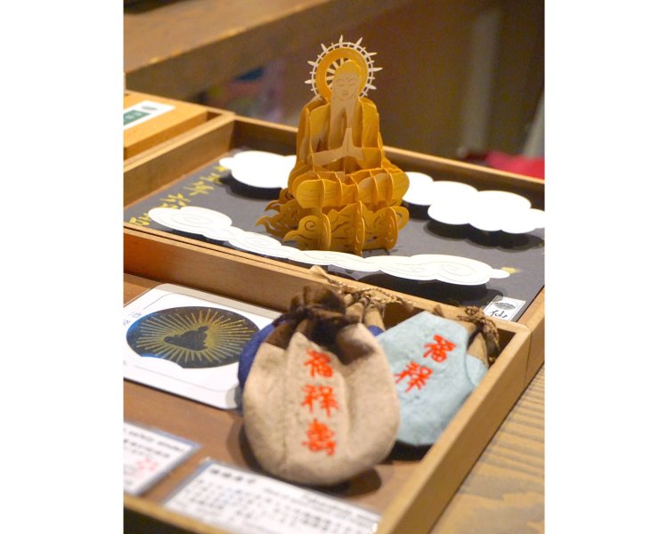 立体ながら御朱印帳にスッと収まる「飛び出す御朱印」。檀家さんのご縁から生まれたラオスの手織りの布製の「福禄寿御守」や、池袋大仏を彫る際に出た木を閉じ込めた「大仏御守」なども。