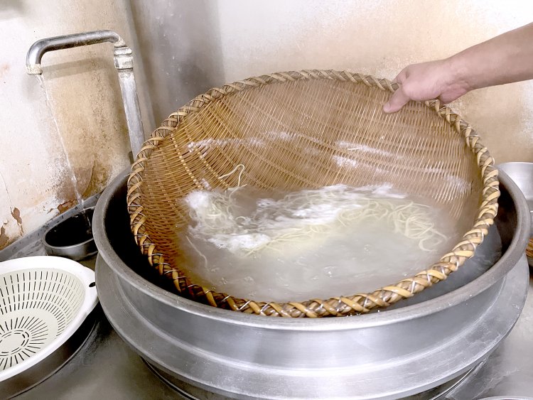 竹ざるを巧みに使って茹でる。