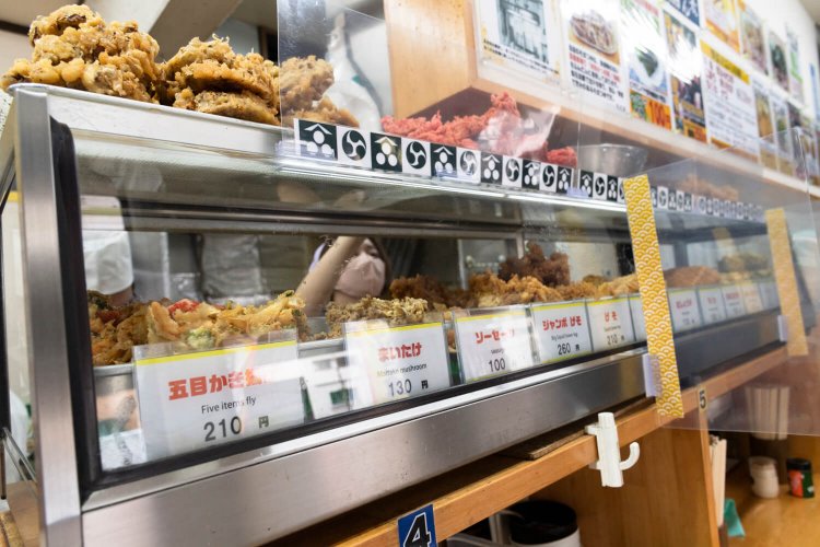 旧店はかき揚げのみだったが、新店ではげそ天や五目かき揚げ210円など天ぷらが充実。