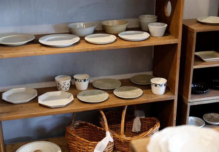 アンティークの棚に並ぶ平皿など。店で扱う器の作家は国内から十数名。