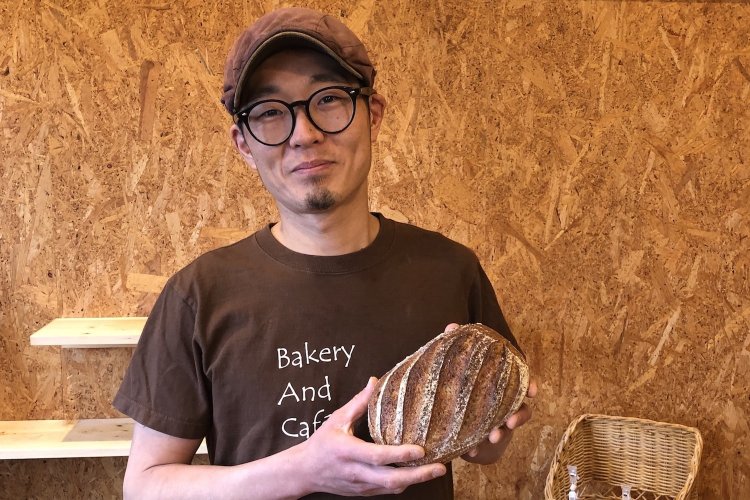 カンパーニュを持って微笑むオーナーシェフ、齋藤さん。