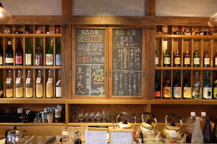 にぎやかな黒板と酒瓶が出迎え「飲むぞ！」と気分が上がる。