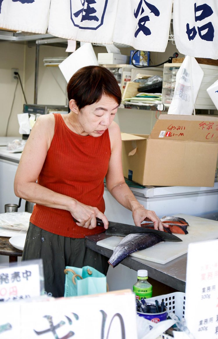 「おにぎりは電話で予約も可能です」。鮭をさばく佐藤さん。店頭では種類豊富な切り身も購入可。