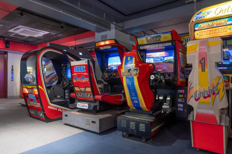 元祖ドライブゲーム「アウトラン」。世界各所を舞台にスポーツカーで駆けめぐる！ （写真は『GiGO 秋葉原3号館 RETRO:G』）。