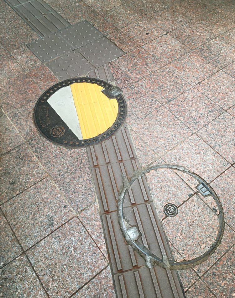 点字ブロックが途切れないよう配慮されたマンホールの蓋。色を合わせるのは面倒だったらしい。