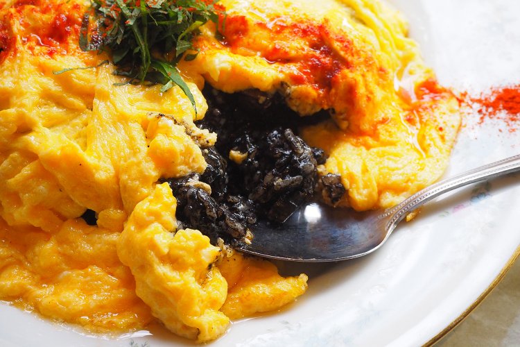 黄金の卵の奥から、真っ黒なご飯が現れる。