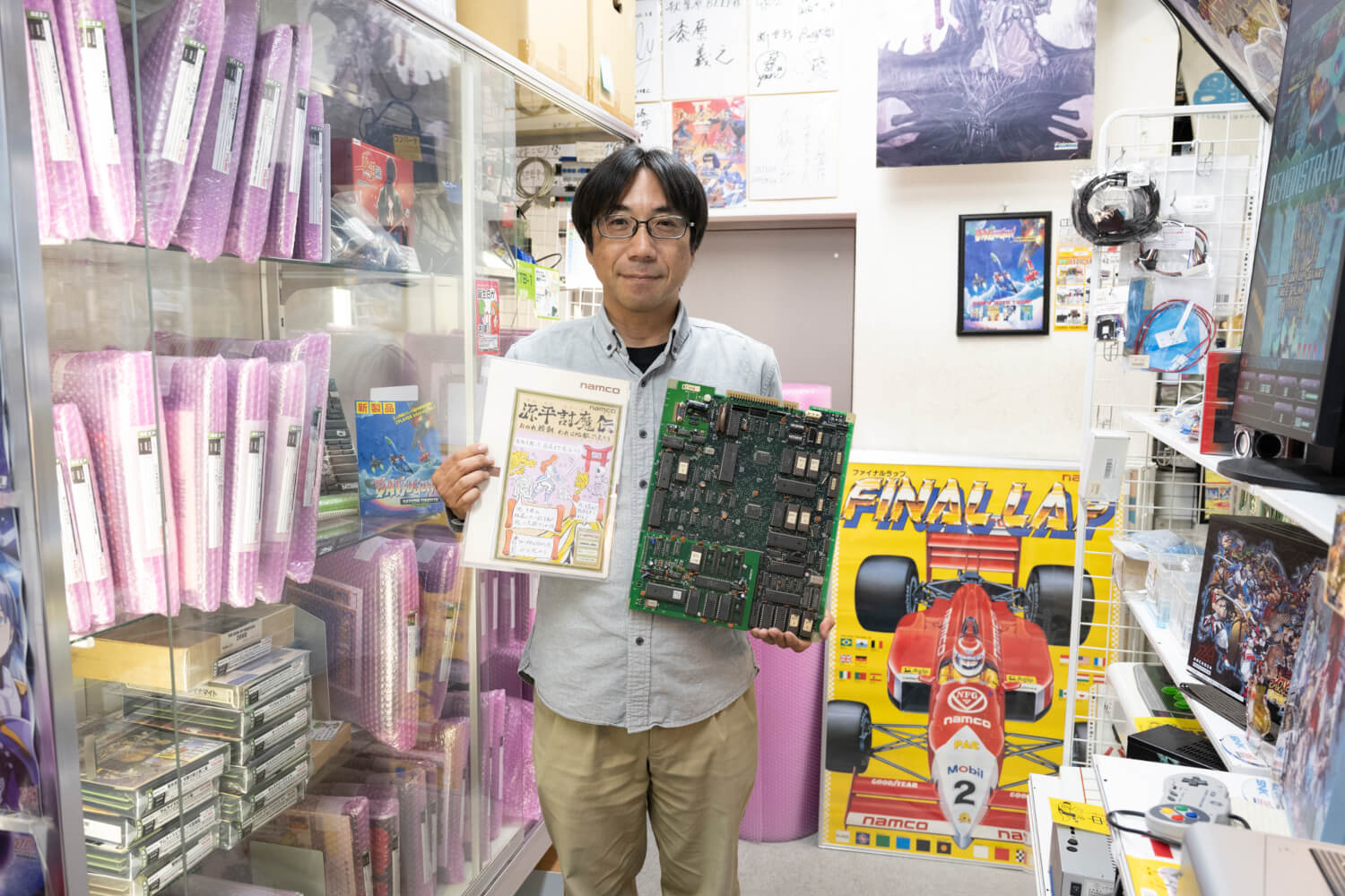 店のプロデューサー・RF丸山氏。持っているのは大好きだという『源平討魔伝』の基板だ。