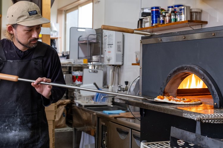 庫内温度400℃もの石窯を自在に操る店主の吉田慶吾さん。