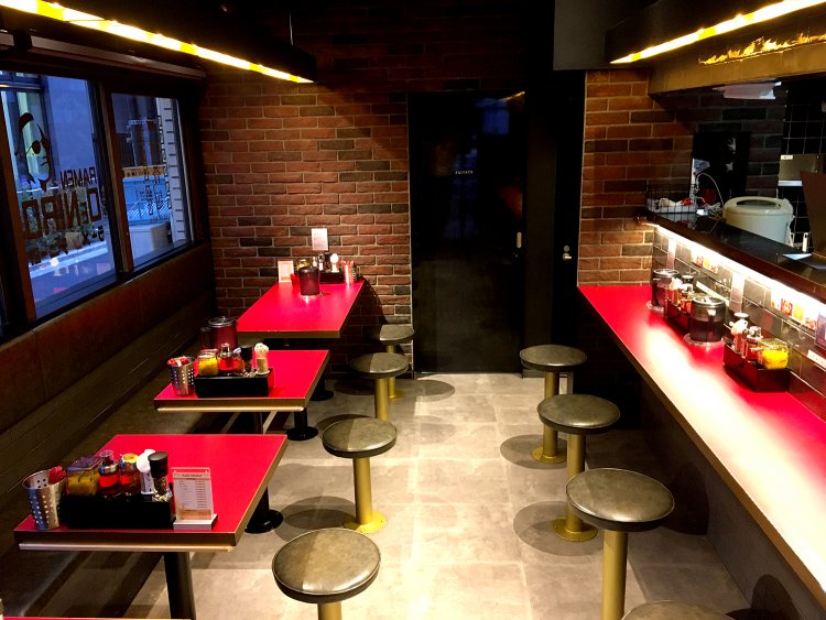 カウンター席が5席とテーブル席が10席。テーブルの赤が印象的だ。