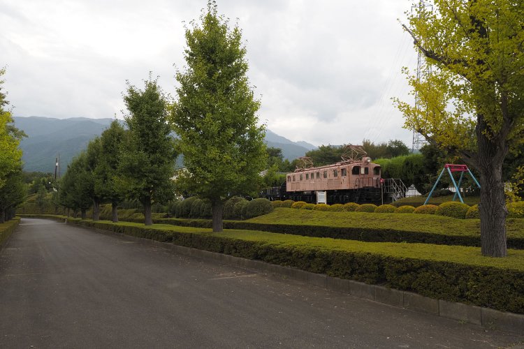 公園の緑地の向こうに佇んでいるEF15形電気機関車。車体色が明るいのが気になる。