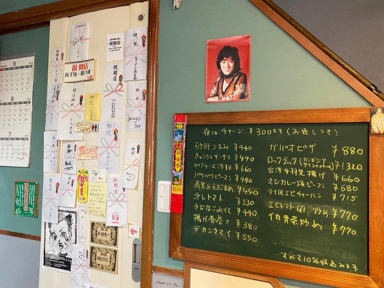 豊富なアジアンフードメニュー。開店時にいただいたお祝いの熨斗がたくさん貼ってあるトイレのドア。実はここの一角に、お得になるキーワードが隠されている。