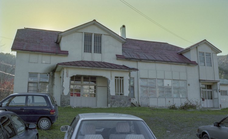 1997年に訪れた旧大夕張鉄道大夕張駅舎。鉄道の廃止後は診療所になった。訪れたときは鹿島地区住民の車が並び、駅舎もまだ活用されていた。1997年秋撮影（カラーネガ）