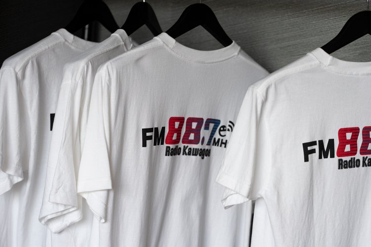 局内の至る所に「FM88.7MHz」のロゴが。オリジナルTシャツ1000円はS～XLあり、HPやイベントで購入可。