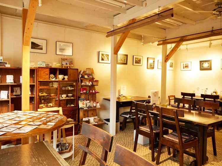 白壁と窓際のテーブルが月替わりのミニギャラリー。食堂だが、コーヒー1杯での利用も可。