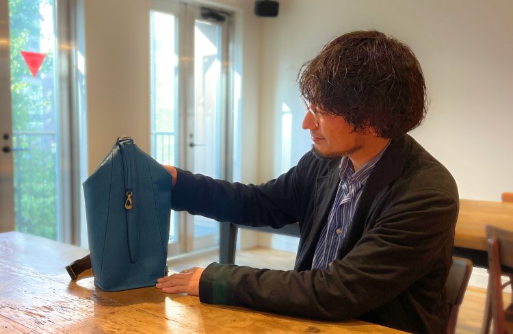 ボディバック「Accel」を持つ石川さん。ボディバッグとしてだけでなく、ハンドバッグにもなる2WAY。「カジュアルになりすぎないスタイリッシュなフォルムは、カフェ巡りにもピッタリです！」