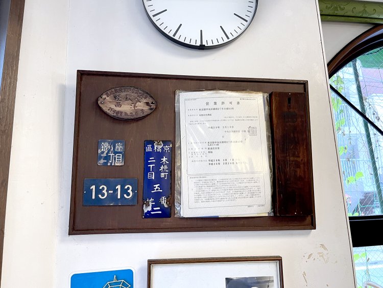 歴代の居住表示プレートや営業許可証が掲示されている。右端の木札の文字は消えかかっているがうっすら「西支料理」の文字が確認できる。
