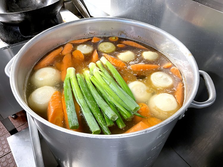 寸胴鍋には香味野菜とともに煮込まれたスープが。「スープの材料は秘密です」と久保さんは話すが、写真を撮らせてくれるやさしさに感謝！