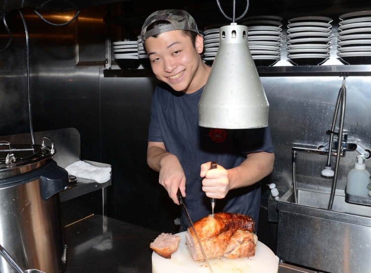 ローストポークの塊を切る副店長の渡部陸斗さん。