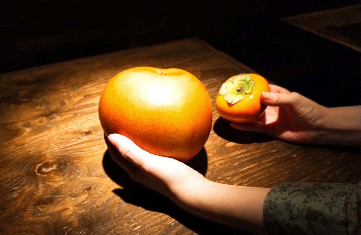 1kg超えの新高梨。筆者の手のサイズと比べても、隣の柿のサイズと比べても、なお大きい。